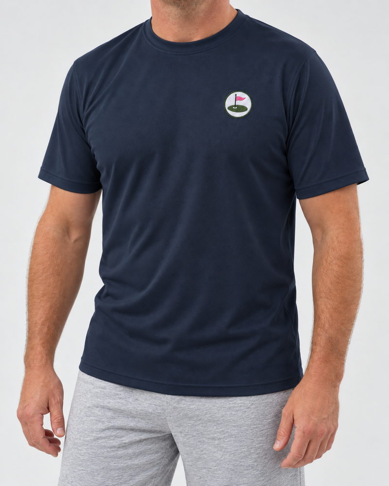 Model wearing the navy Seabury performance tee with embroidered chest roundel and light grey marl shorts.