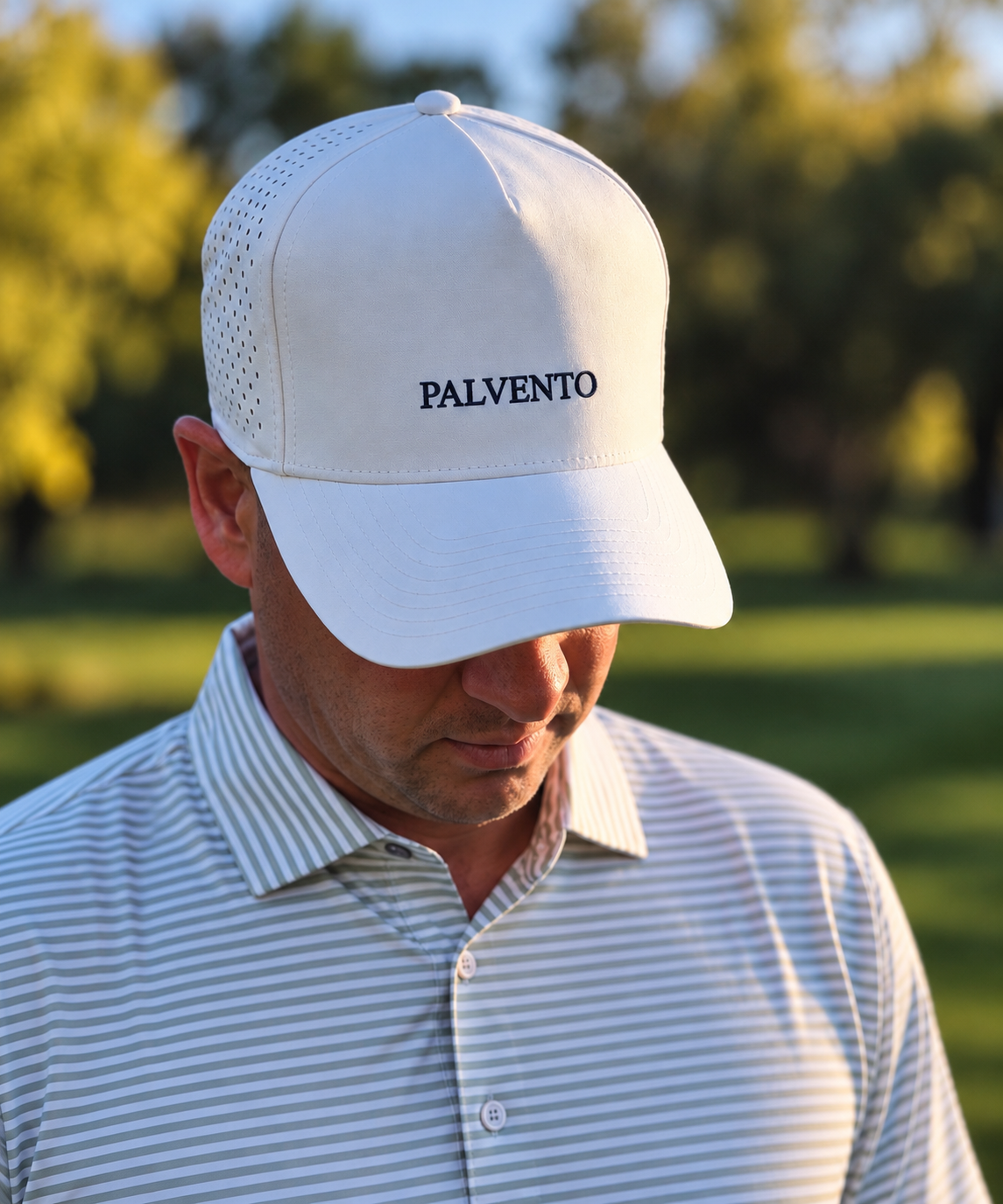 Palvento Golf founder Nick wearing a white Palvento embroidered cap and striped golf polo on a British golf course, reflecting the brand’s understated British golfwear style.