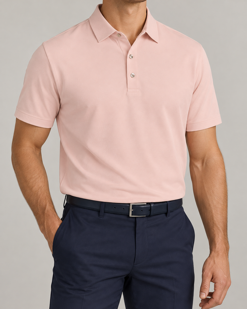 Palvento Ainsdale peach pink golf polo on a model, styled with an open collar and navy trousers.